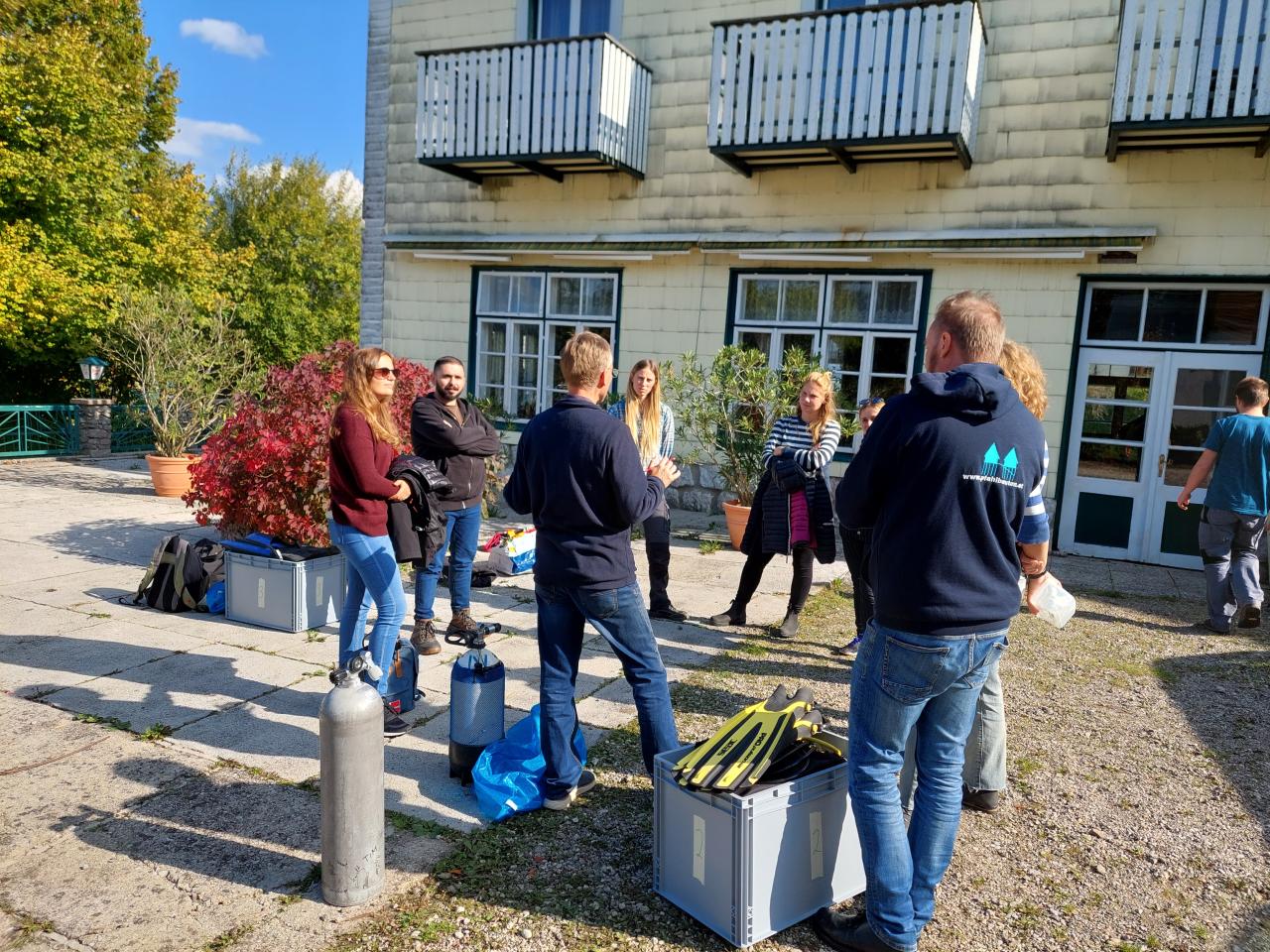 Eine Personengruppe steht vor einem Haus im Kreis