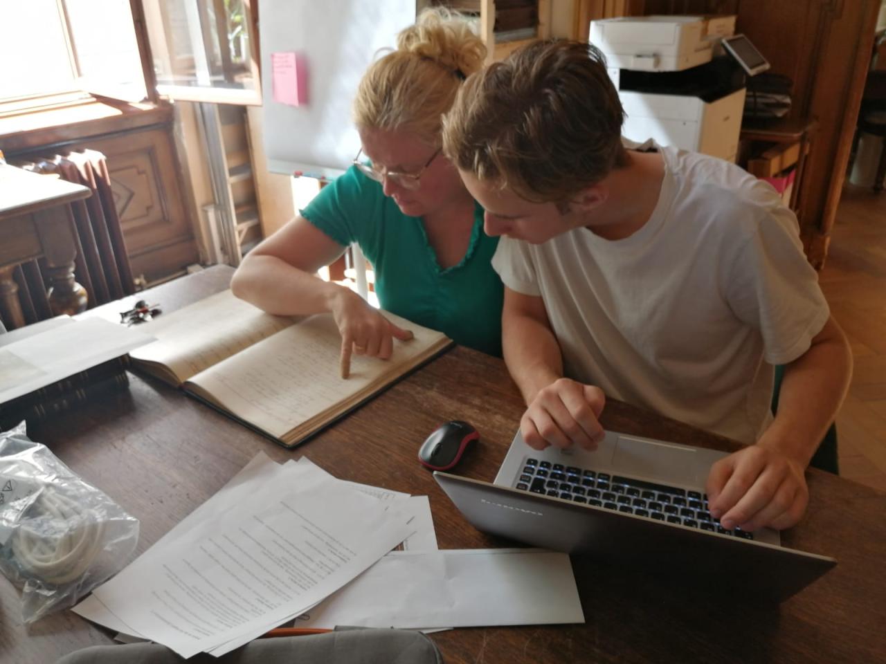 Karina Grömer und Michael Lonsing vor einem Laptop und einem Buch