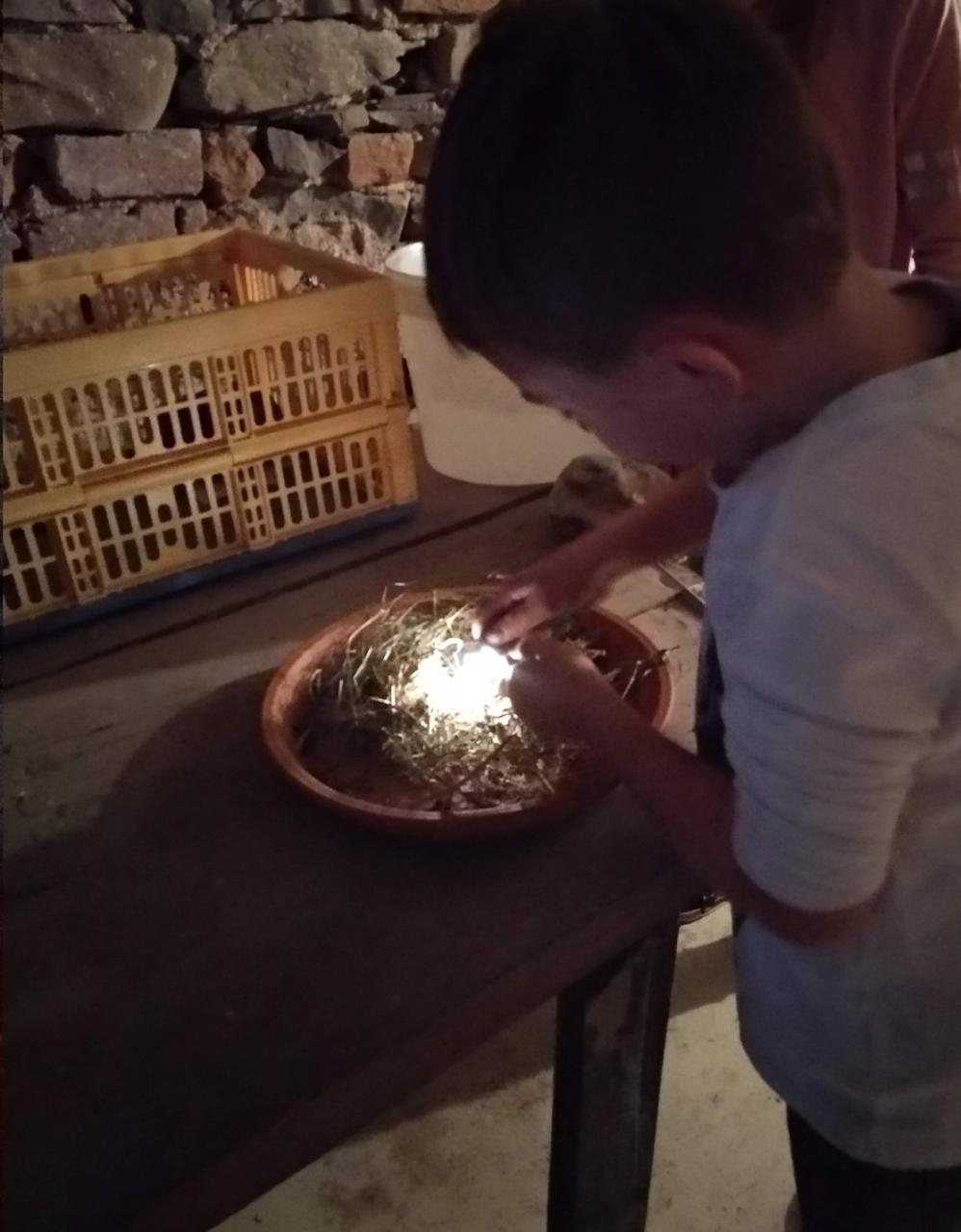 Ein Kind entzündet trockenes Gras mit einem Funken