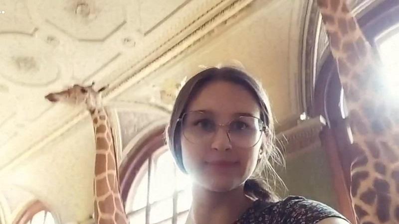 Eine junge Frau mit Brille, vor 2 Giraffen
