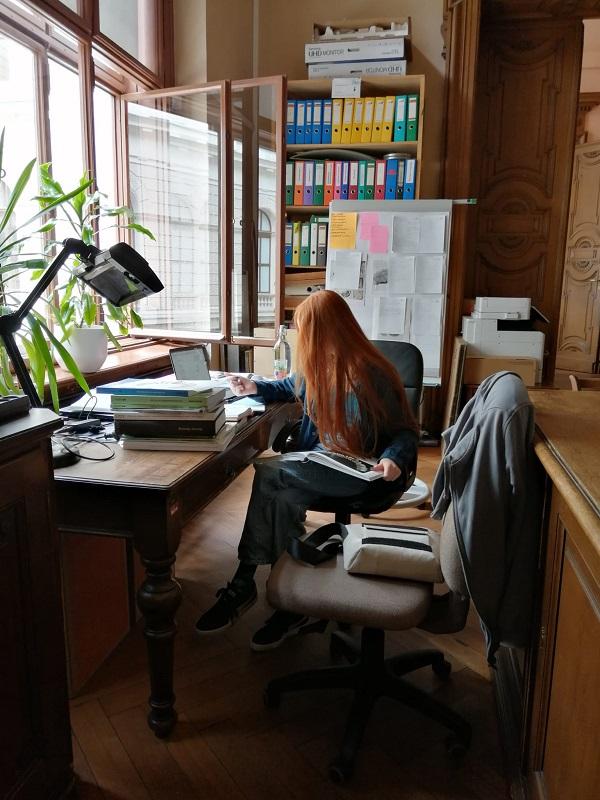 Eine Frau vor einem Schreibtisch über die Arbeit gebeugt