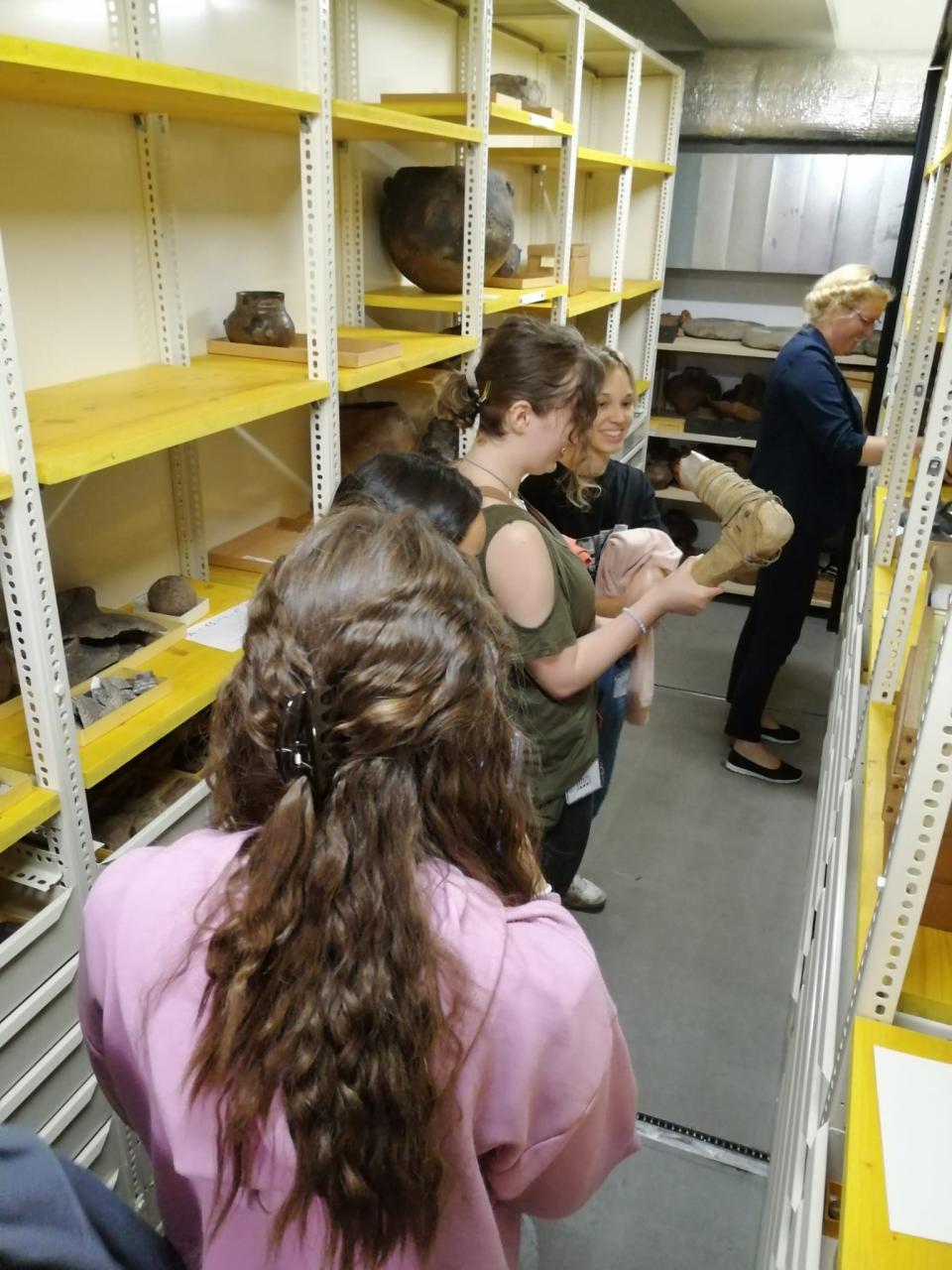4 Personen stehen zwischen 2 Regalen im Tiefspeicher des Naturhistorischen Museums Wien