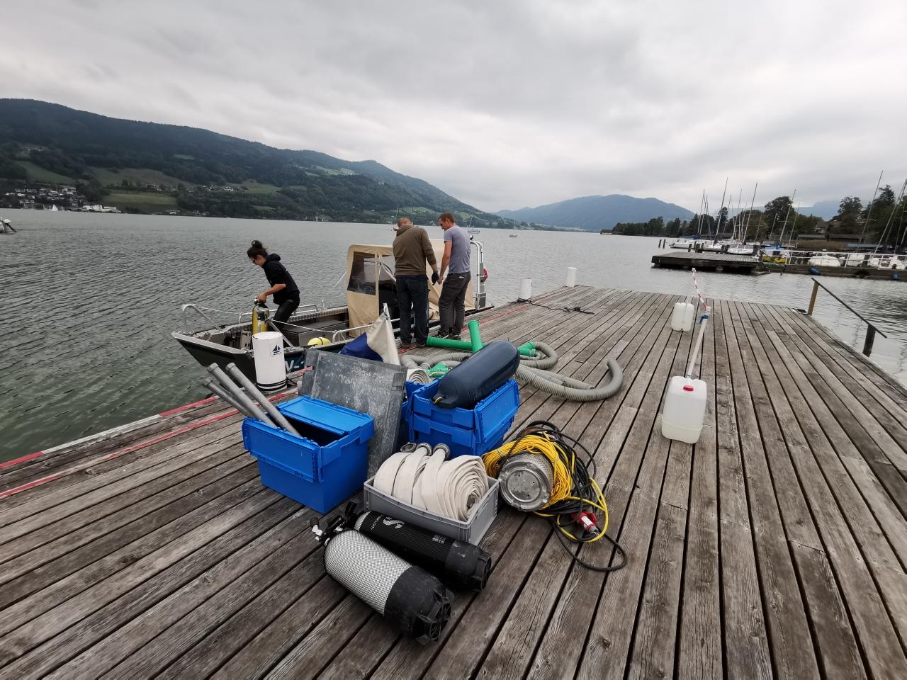 Tauchequipment liegt auf einem Steg und wird auf ein Boot verladen