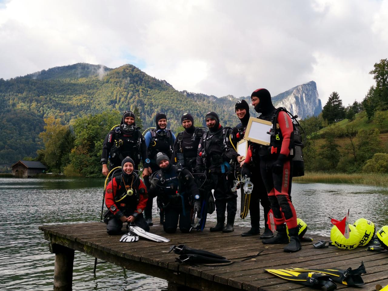 Eine Gruppe von Taucher:Innen auf einem Steg in Taucheranzügen