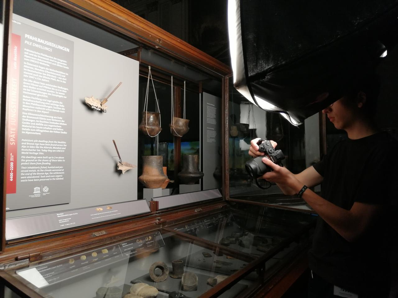 Eine Person fotografiert Fundstücke in einer Vitrine