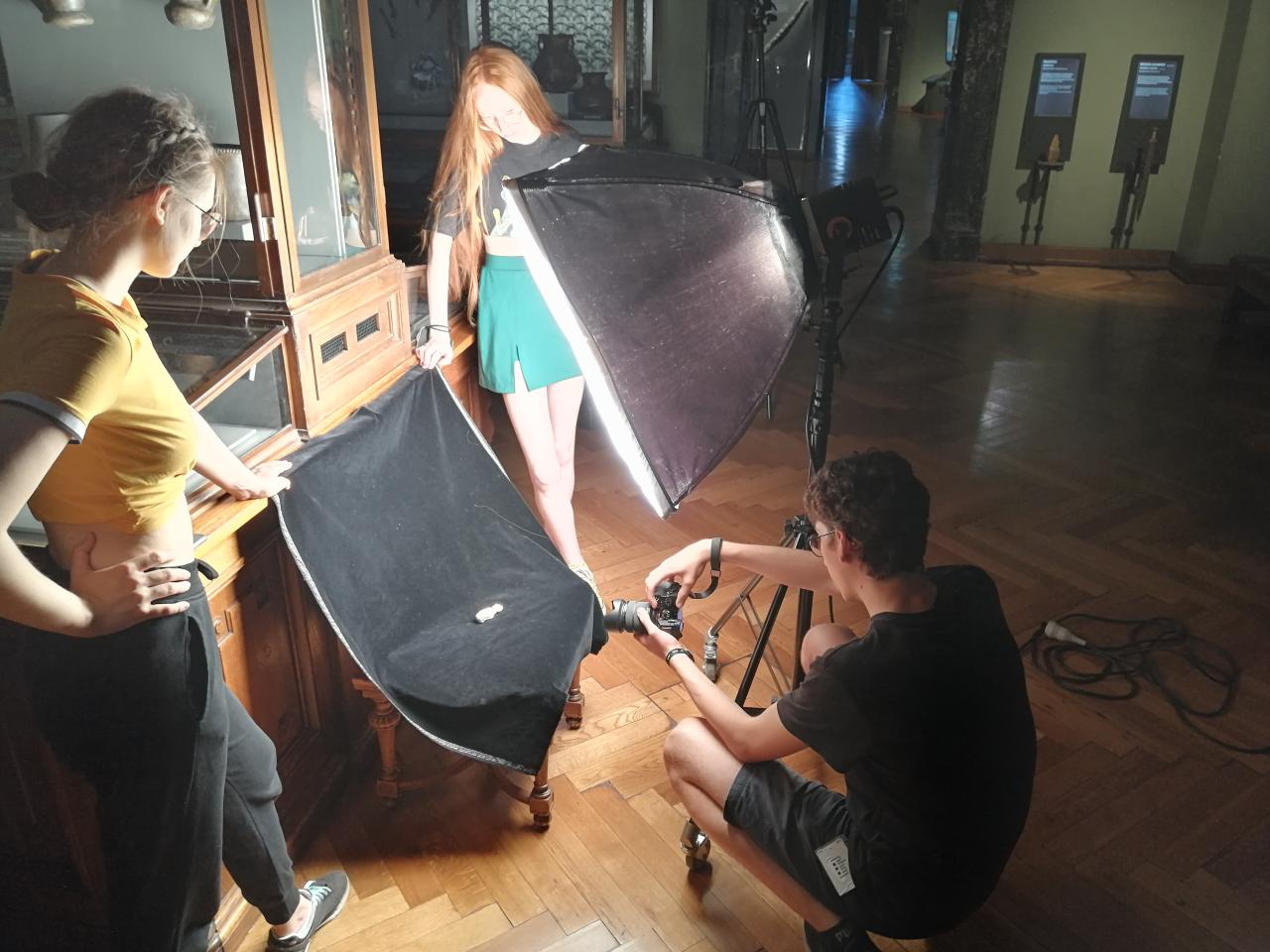3 Personen fotografieren ein Fundstück mit Beleuchtung vor einer Vitrine