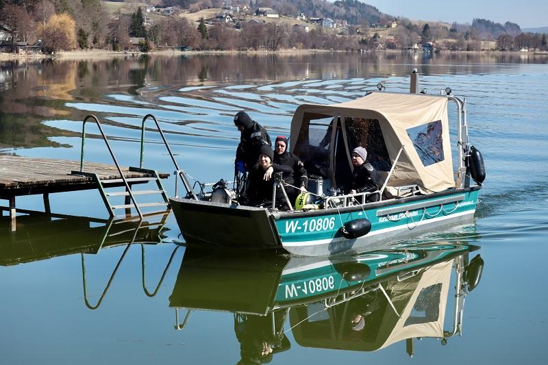Ein Motorboot legt am Steg an, auf dem Boot befinden sich 3 Taucher