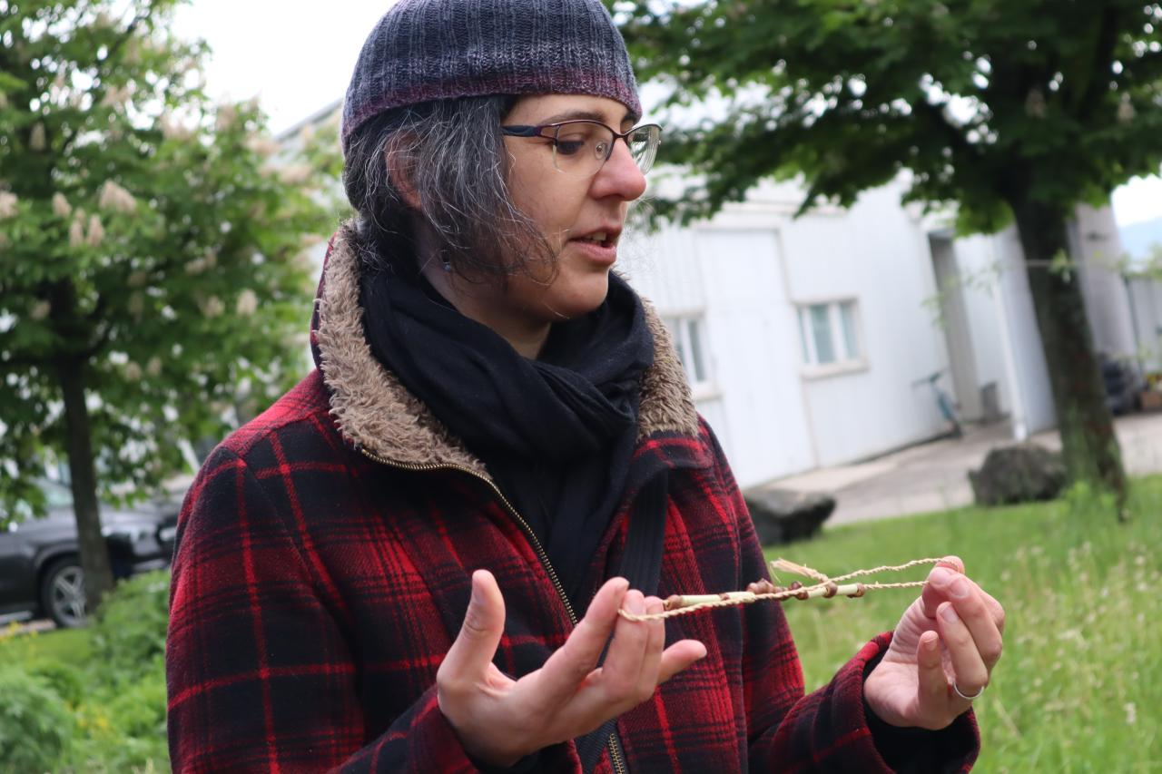 Eine Frau mit Mütze zeigt eine Bastschnur