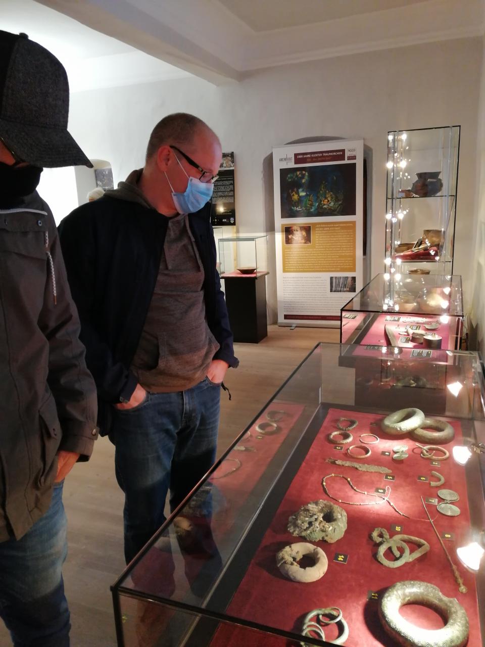 2 Personen mit Atemschutzmaske stehen vor einer Vitrine in einem Museum