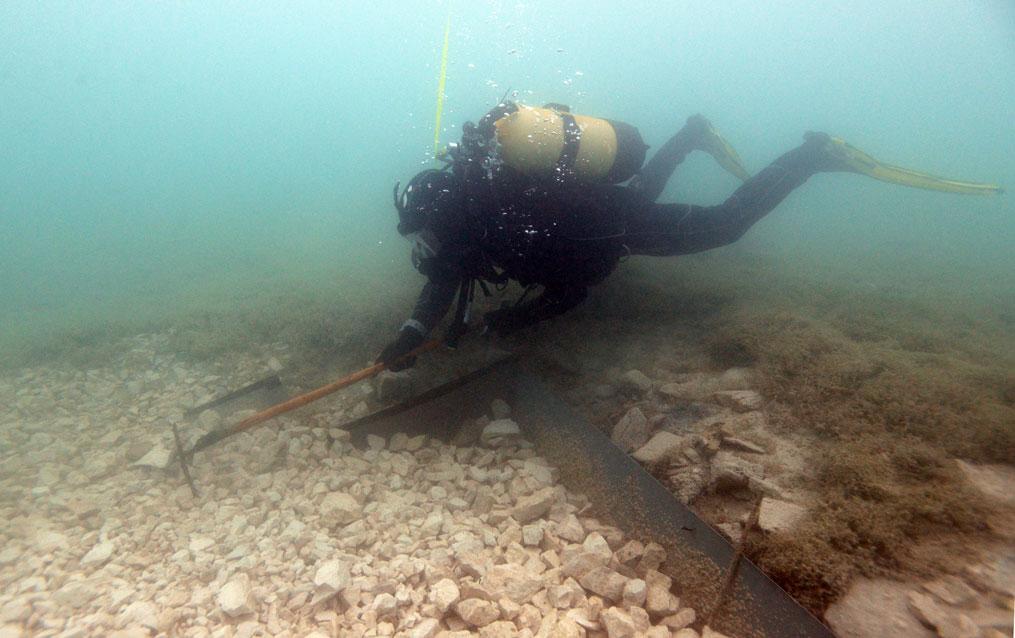 Ein Taucher, der Kies unter Wasser harkt