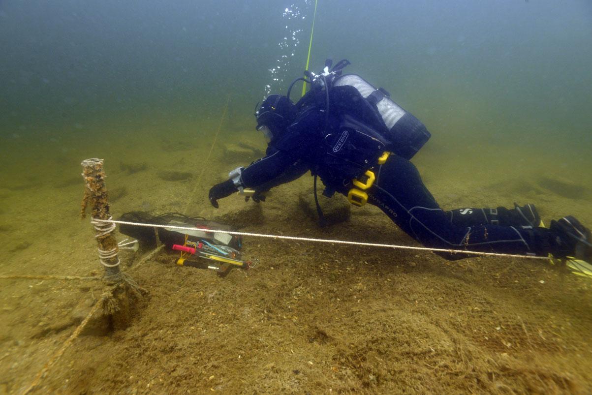 Ein Taucher, der unter Wasser entlang einer gespannten Schnur etwas misst