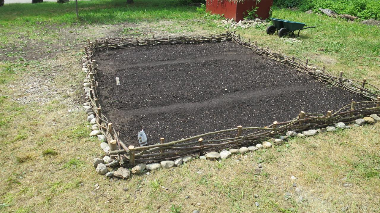 Ein leeres Beet, dass mit einem Rutengeflecht eingefasst ist