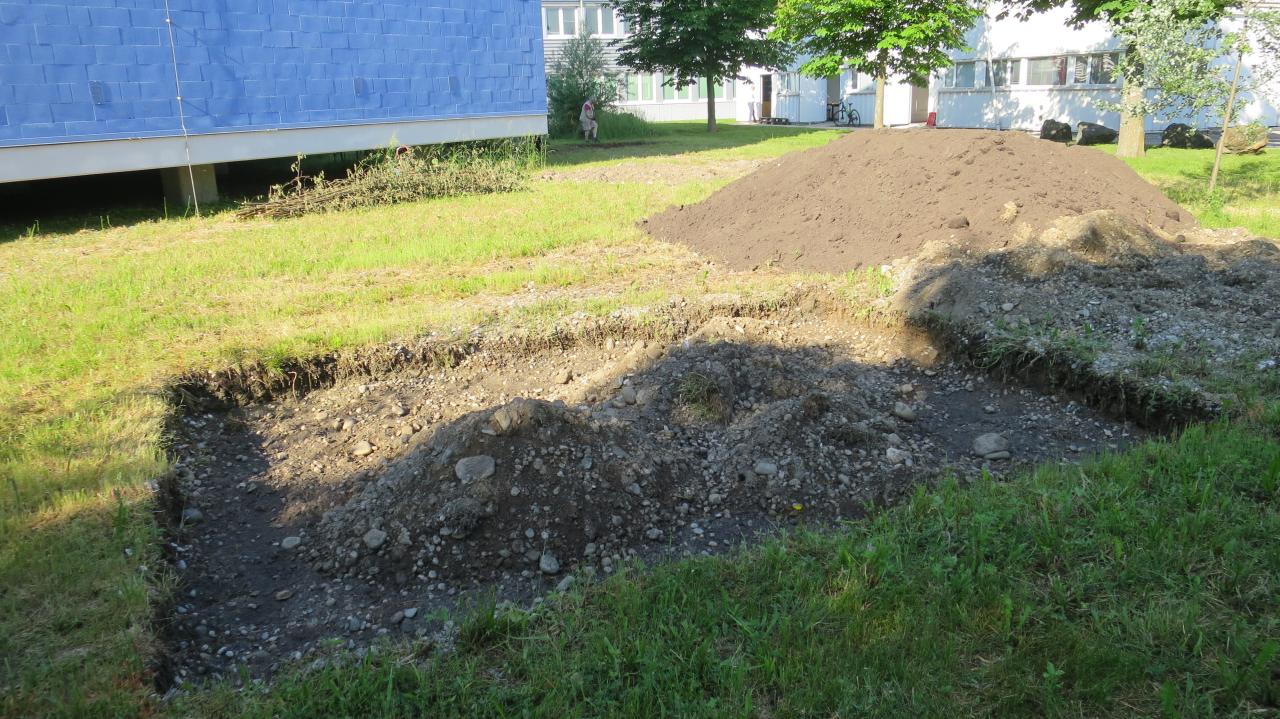 Eine flach ausgehobene Grube in einer Wiese