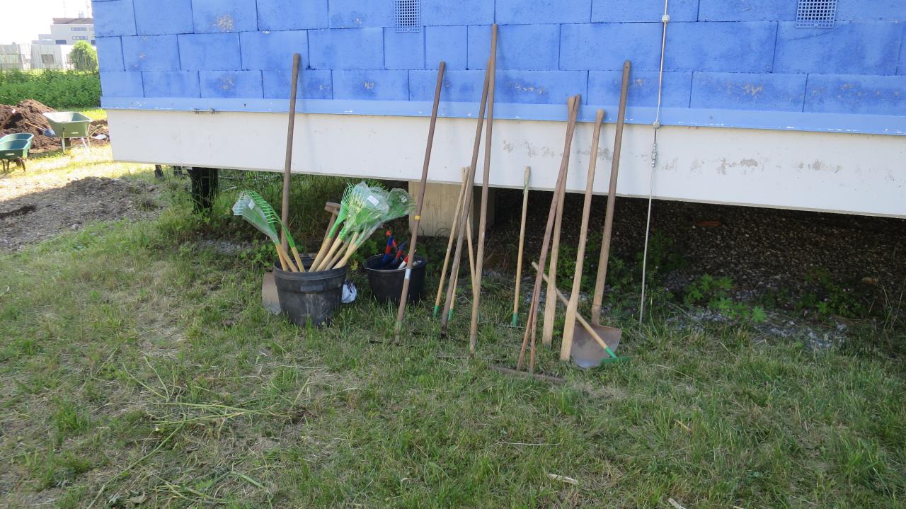 Verschiedene Gartengeräte lehnen an einer blauen Wand
