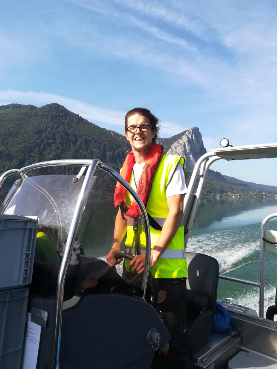 Michael Westerkam mit einer Schwimmweste am Steuer des Motorbootes