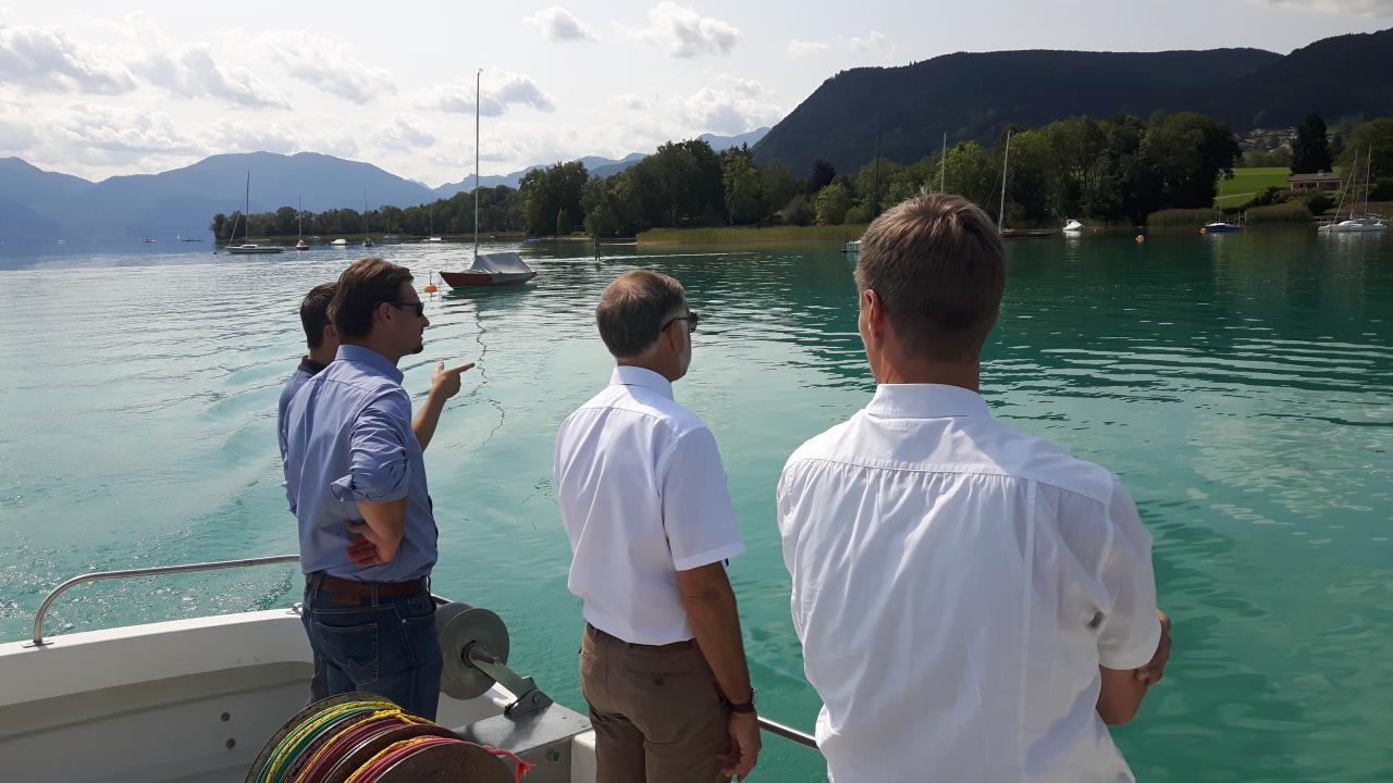 4 Personen stehen auf einem Boot und betrachten den See