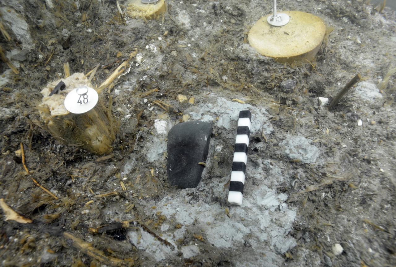 Ein steinernes Flachbeil am Seeboden mit Maßstab