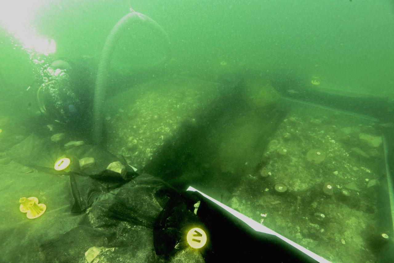 Eine offene Grabungsfläche unter Wasser, die von einem Taucher gesäubert wird