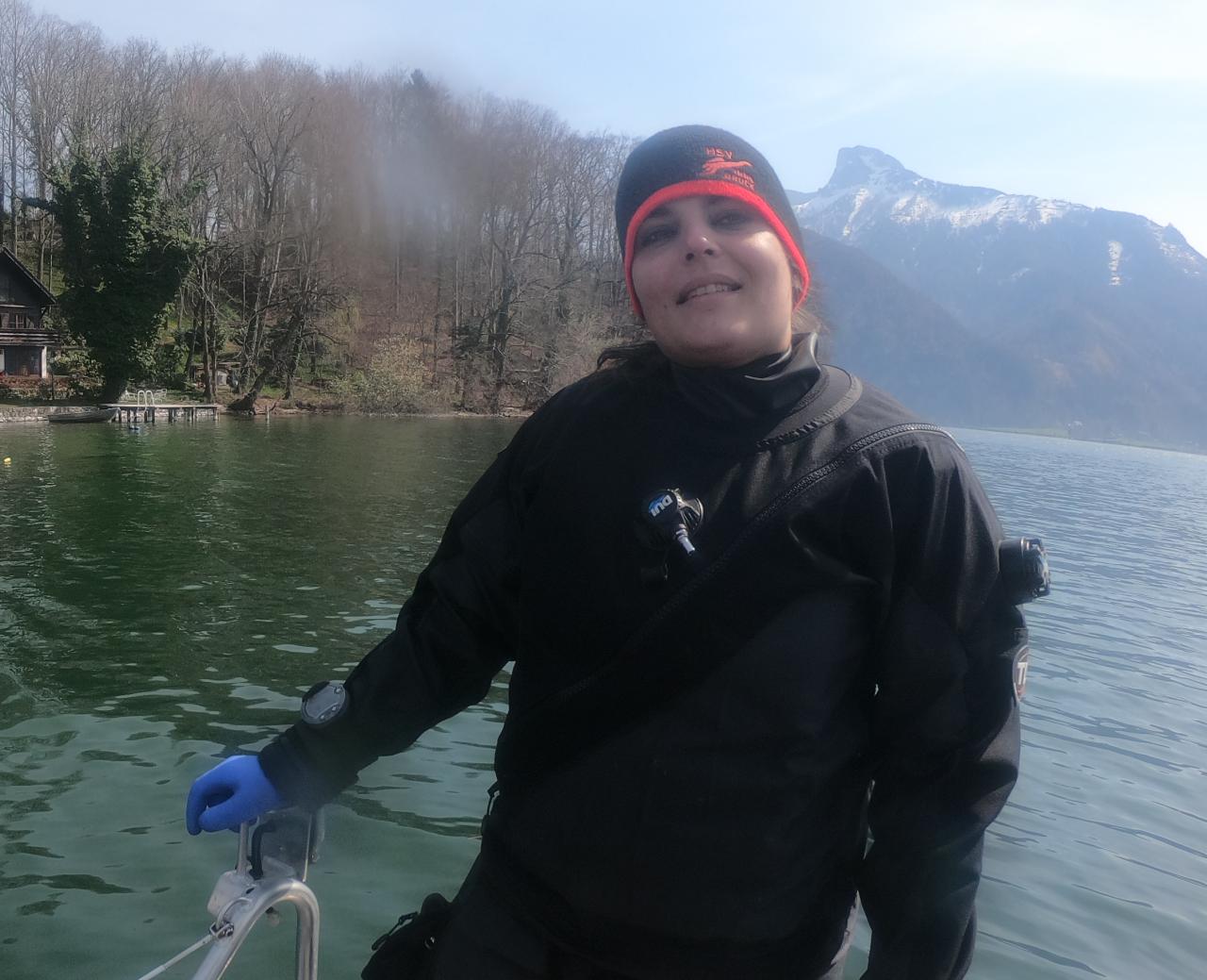 Eine Frau im Tauchanzug steht auf einem Boot, das im See schwimmt