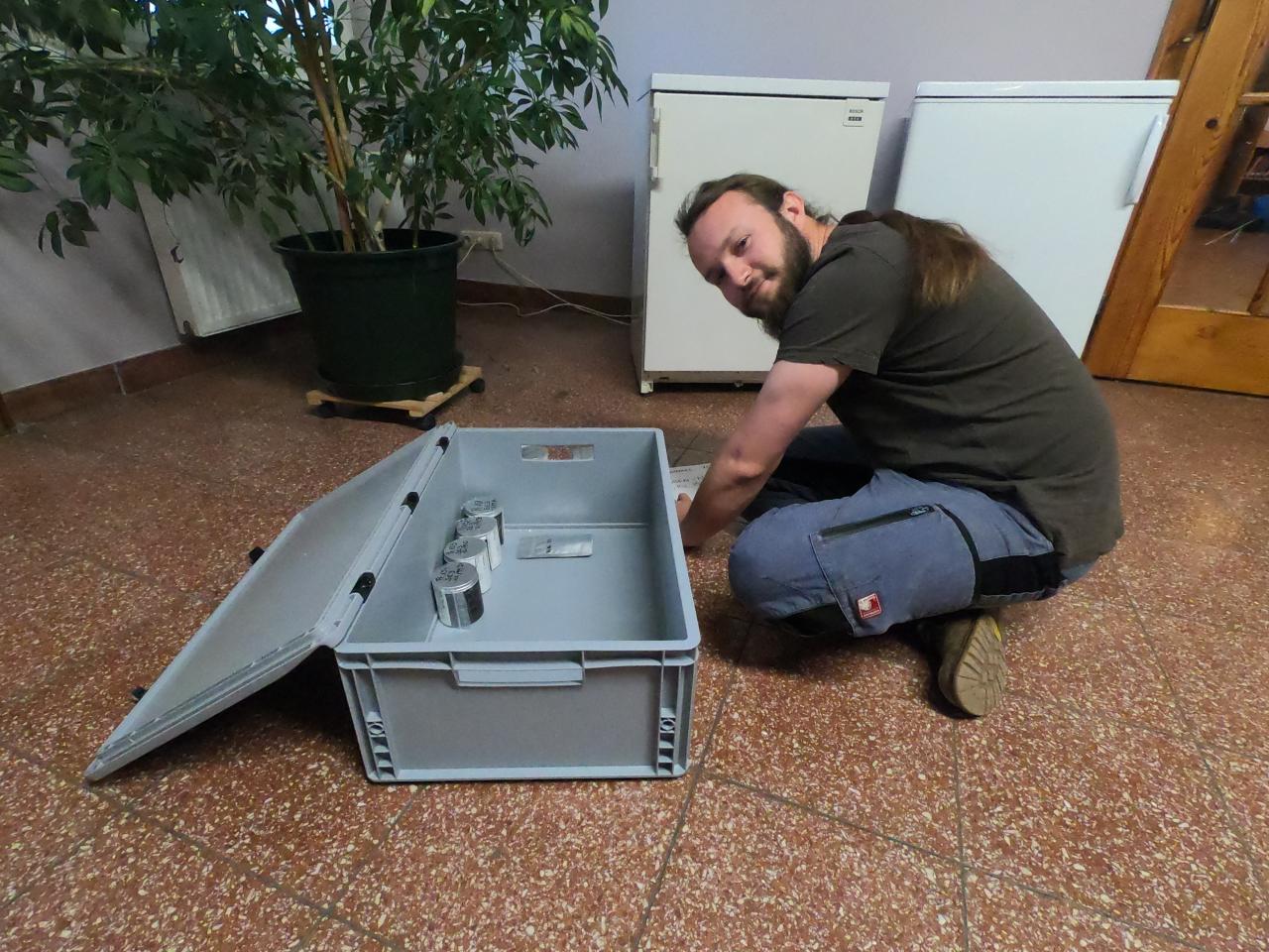 Samuel sitzt im Schneidersitz vor einer Fundkiste