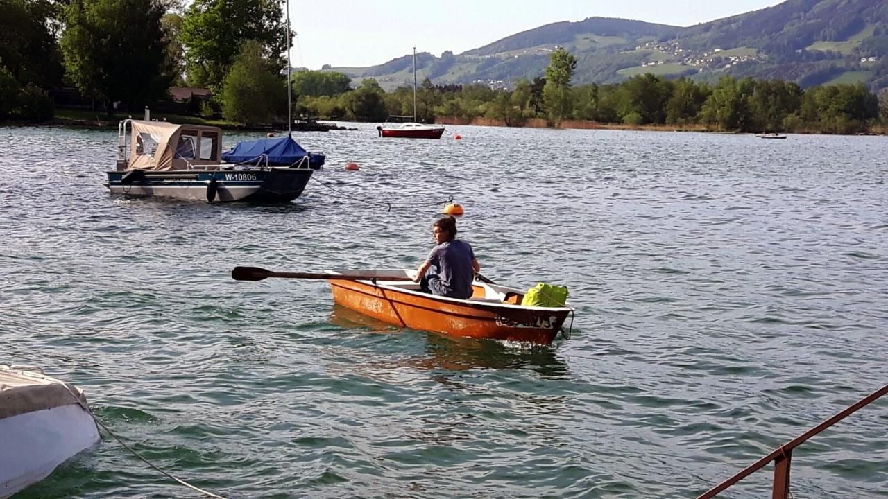 Michael fährt mit einem Ruderboot zum Forschungsboot, welches im See ankert.