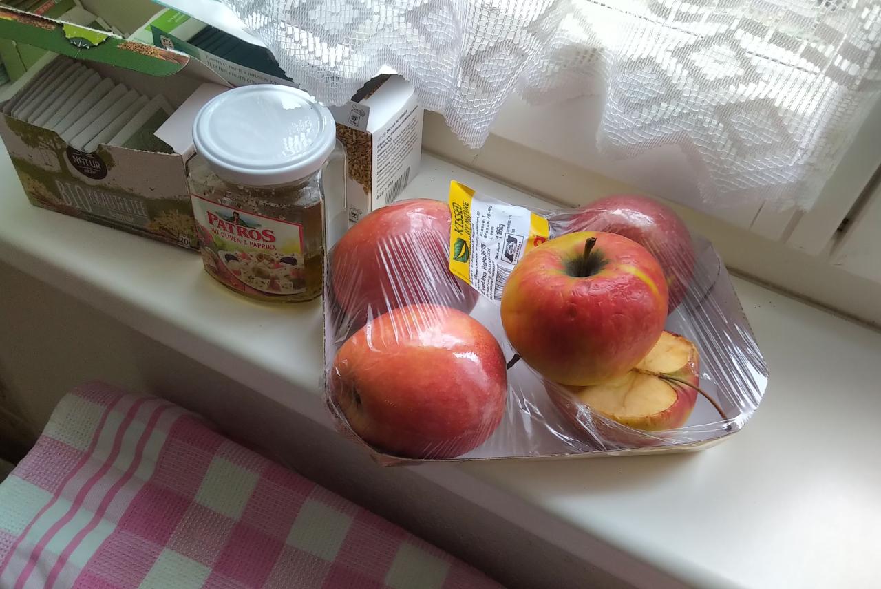 Ein Tasse mit Äpfeln liegt auf einer Fensterbank