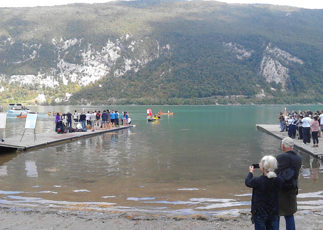 Mehrere Menschengruppen auf Stegen und dem Strand sind Zuseher der Einbaumregatta