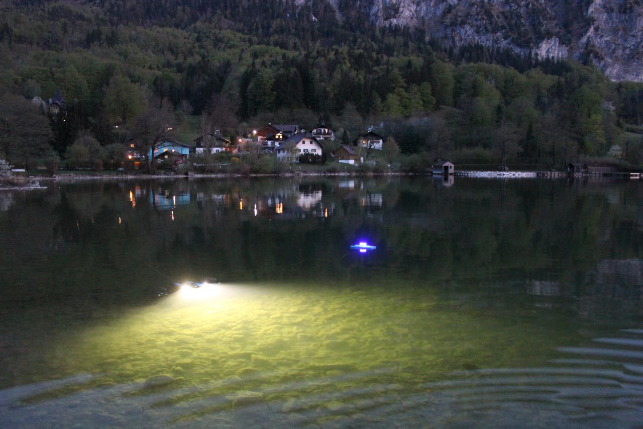 Ein See in der Dunkelheit, man sieht Lichter unter Wasser