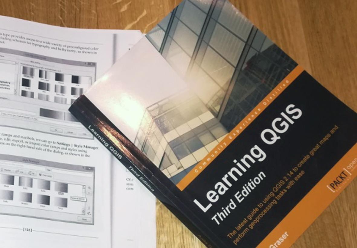 Ein Buch "Learning QGIS" auf einem weiteren geöffneten Buch