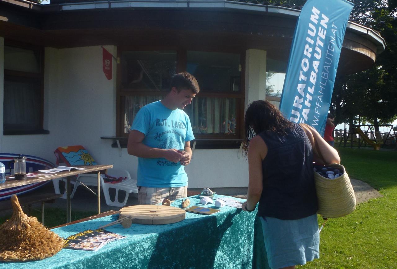 Florian steht am Stand der Kuratoriums und zeigt einer Besucherin die Funde