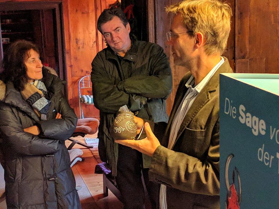 Henrik Pohl zeigt 2 Personen einen Pfahlbaukrug