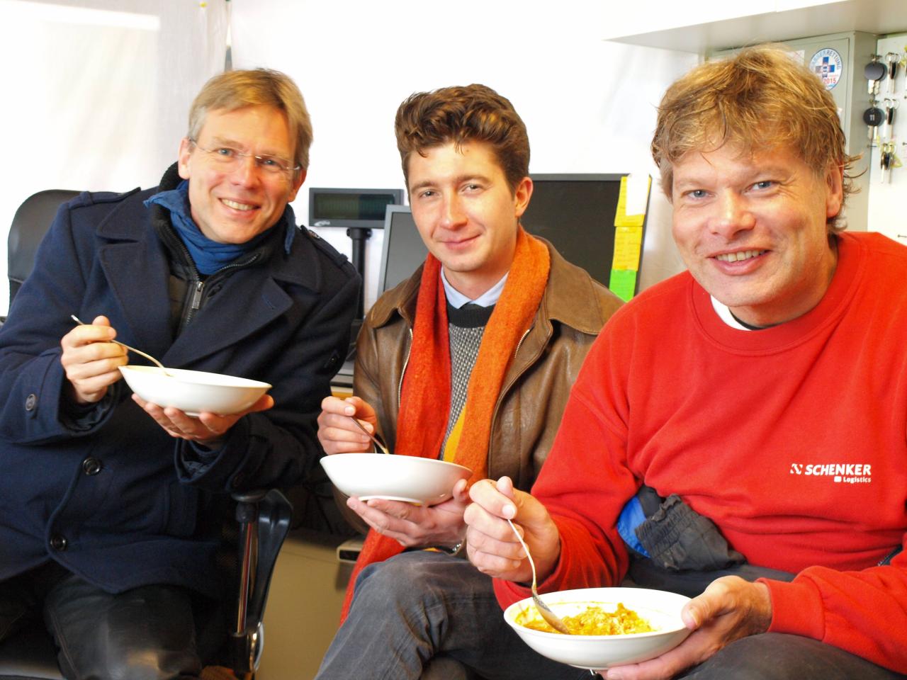 3 Personen sitzen mit Schüsselchen voll Curry im Büro