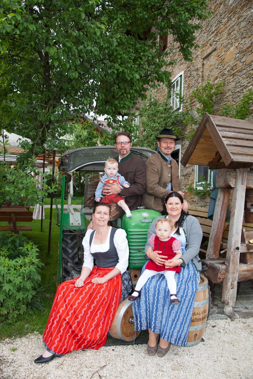 Die Familie Kaltenböck in Tracht vor einem Traktor auf dem Gelände des Bauernhofes