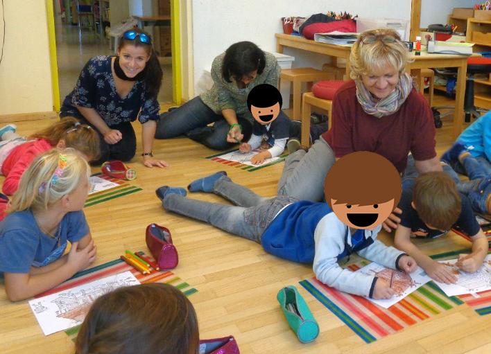 Eine Kindergruppe liegt malend auf dem Boden