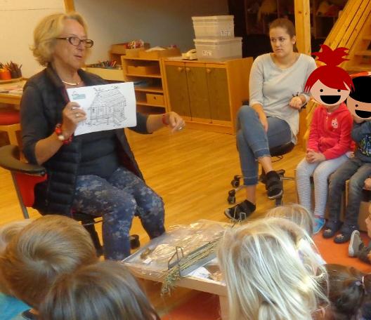 Helga Oeser erklärt einer Kindergruppe anhand von Bildern etwas über die Welterbestätten