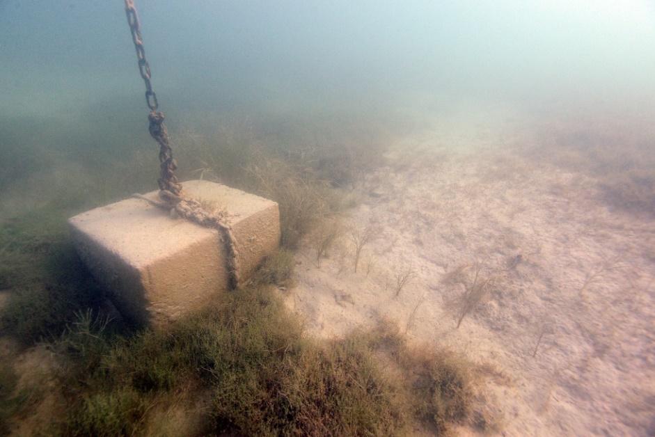 Ein angeketteter Zementblock am Seeboden auf dem befüllten Bojenkrater