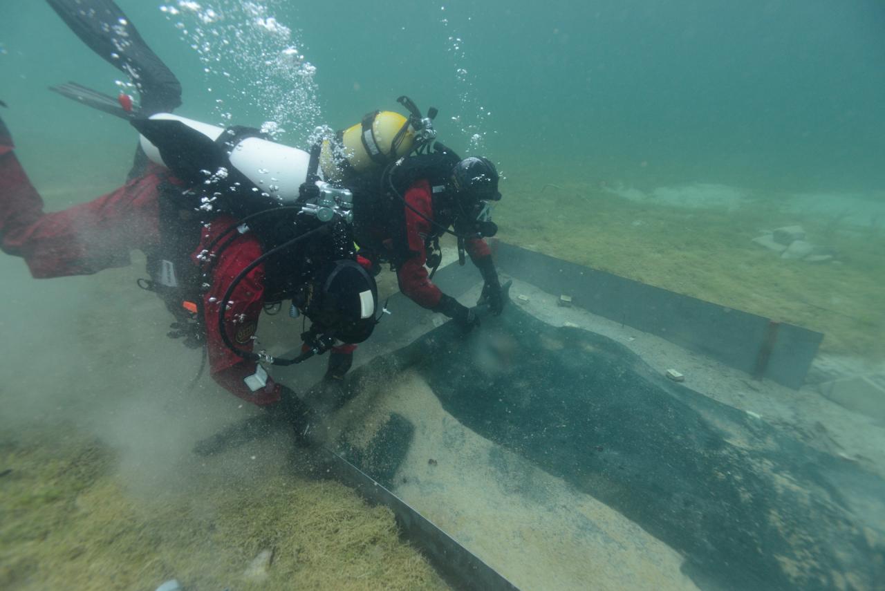 2 Taucher entfernen die Basaltmatten, die als Winterabdeckung auf dem Unterwasserschnitt lag