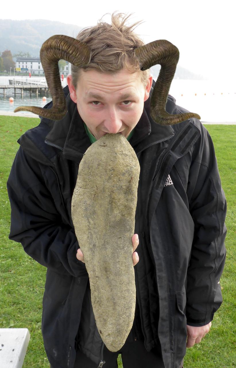 Ein junger Mann, der einen langen Stein als Zunge verwendet und dem Widderhörner auf den Kopf retuschiert wurden