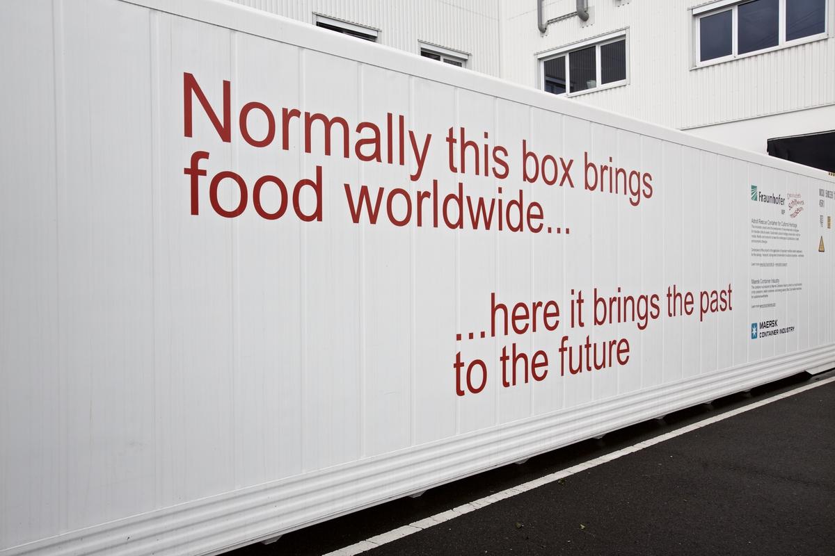 Die Seitenansicht des Containers mit der Aufschrift: "Normally this box brings food worldwide .... here it brings the past to the future