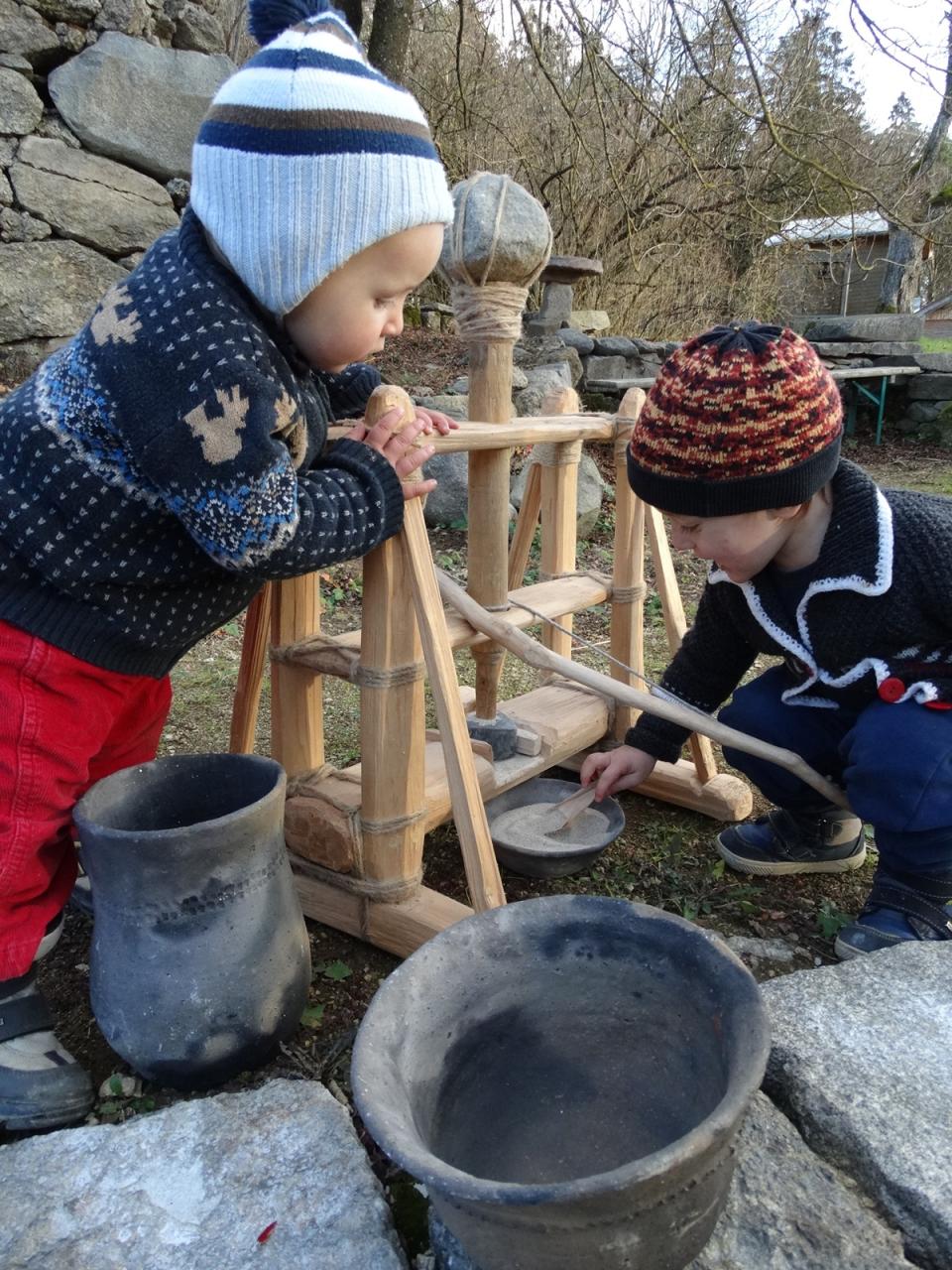 2 Kleinkinder beim Mahlen von Mehl