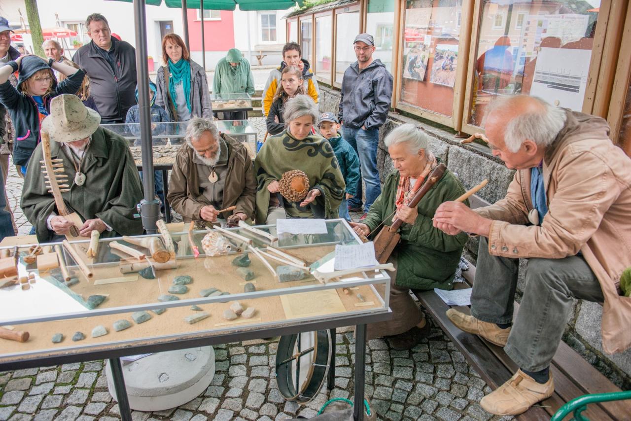 Eine Personengruppe rund um eine Schauvitrine auf einem öffentlichen Platz