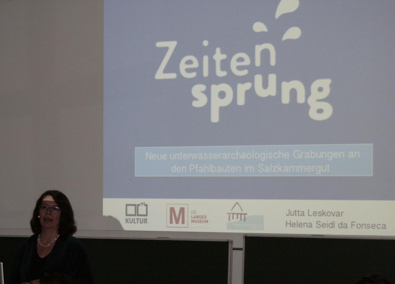 Jutta Leskovar am Rednerpult vor der Leinwand mit dem Zeitensprung Logo