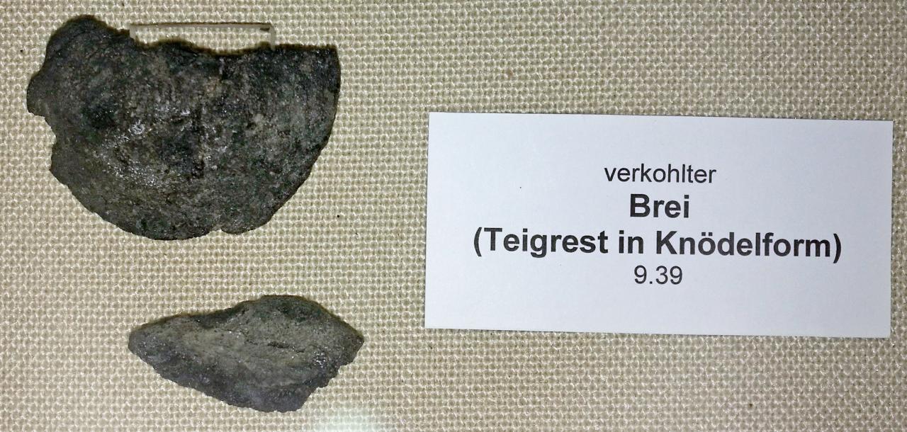 verkohlter Brei (Teigrest in Knödelform) aufgelegt auf einem Textil