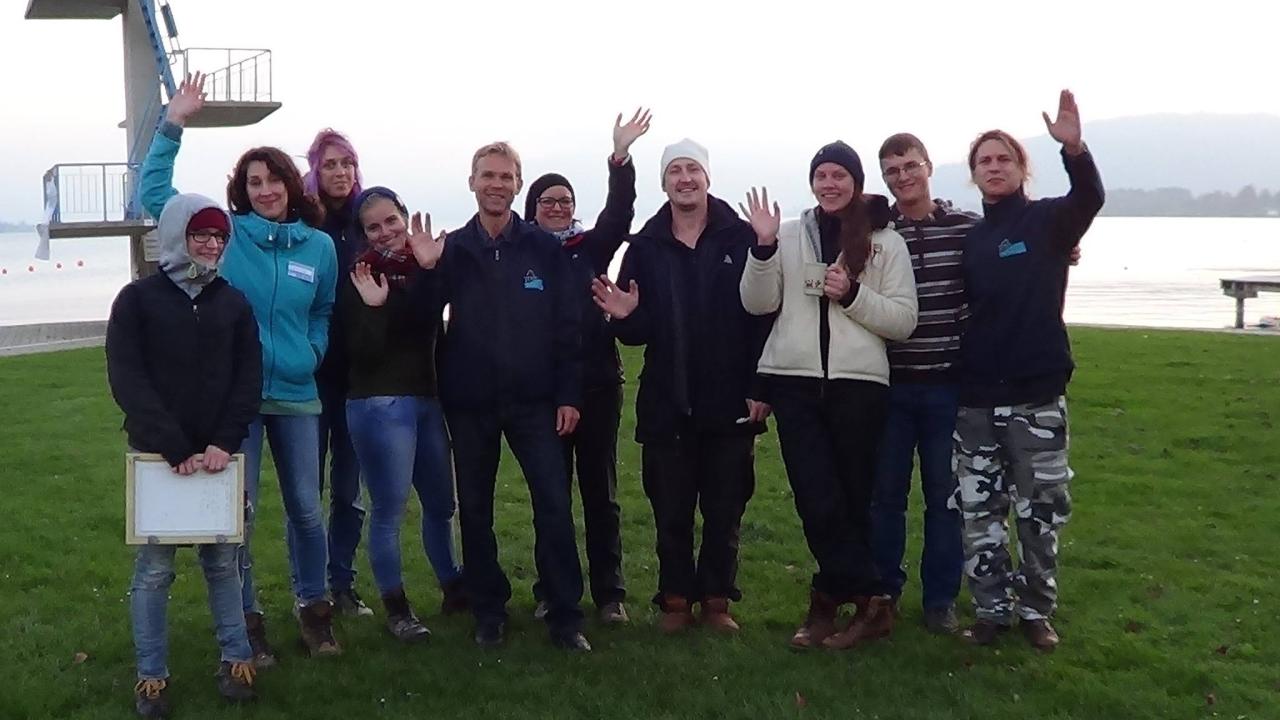 Ein Gruppenfoto des Teams vor dem See und dem Sprungturm