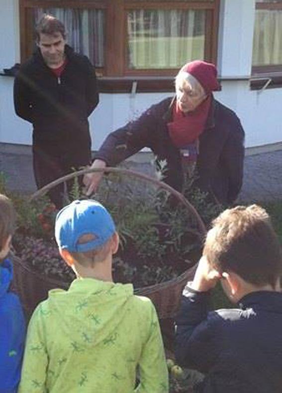 Bärbel erklärt einer Schülergruppe etwas von Pflanzen, die in einem Korb drapiert sind