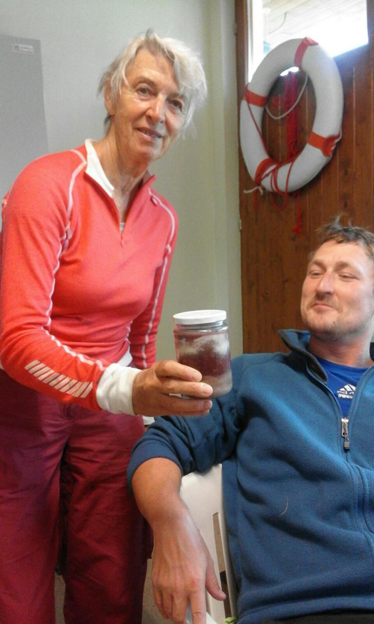 Eine Frau übergibt einem Mann ein Glas mit Hühnersuppe