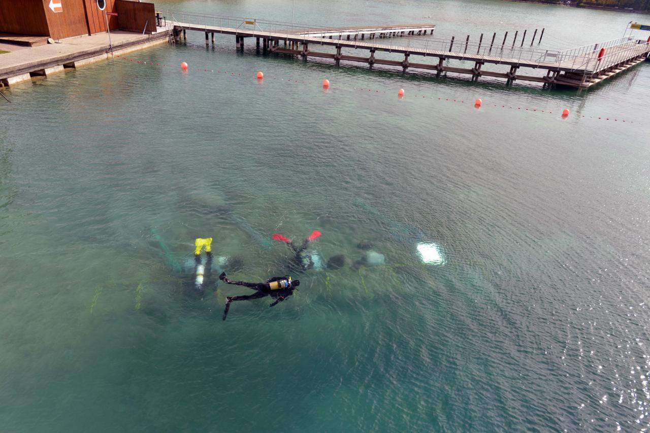 Man erkennt die Taucher unter der Wasseroberfläche bei der Arbeit im Grabungsschnitt