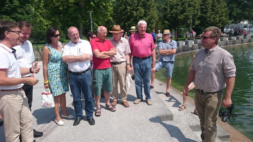 Eine Menschengruppe steht am Ufer des Attersees und unterhält sich