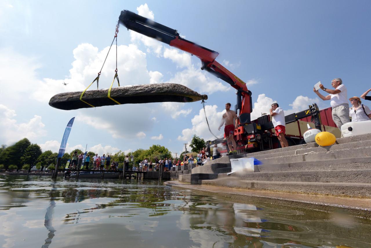 Ein Kran hebt den Einbaum aus dem Wasser