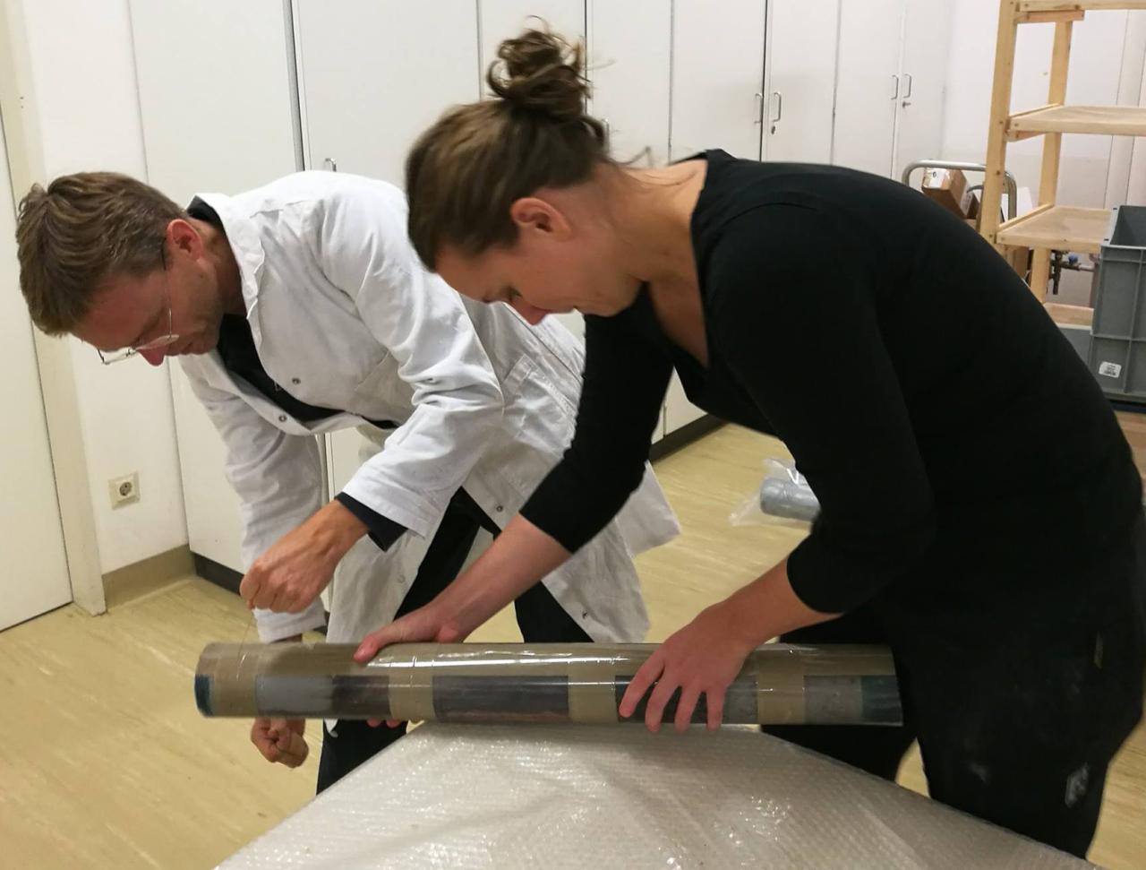 Henrik und Helena halten den Bohrkern in Händen und Öffnen ihn vorsichtig